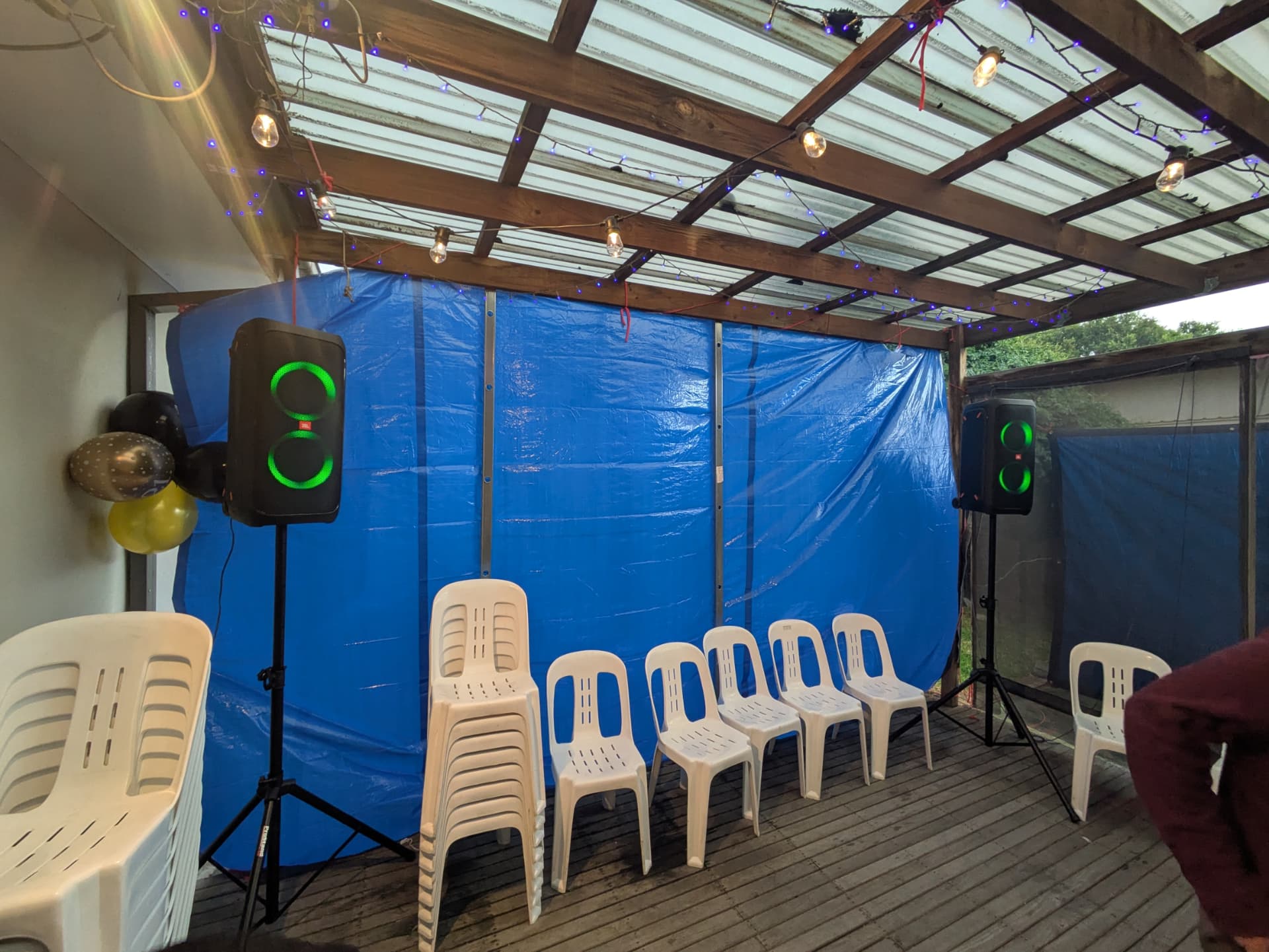 Speakers on stands either side of a backyard patio ceremony setup