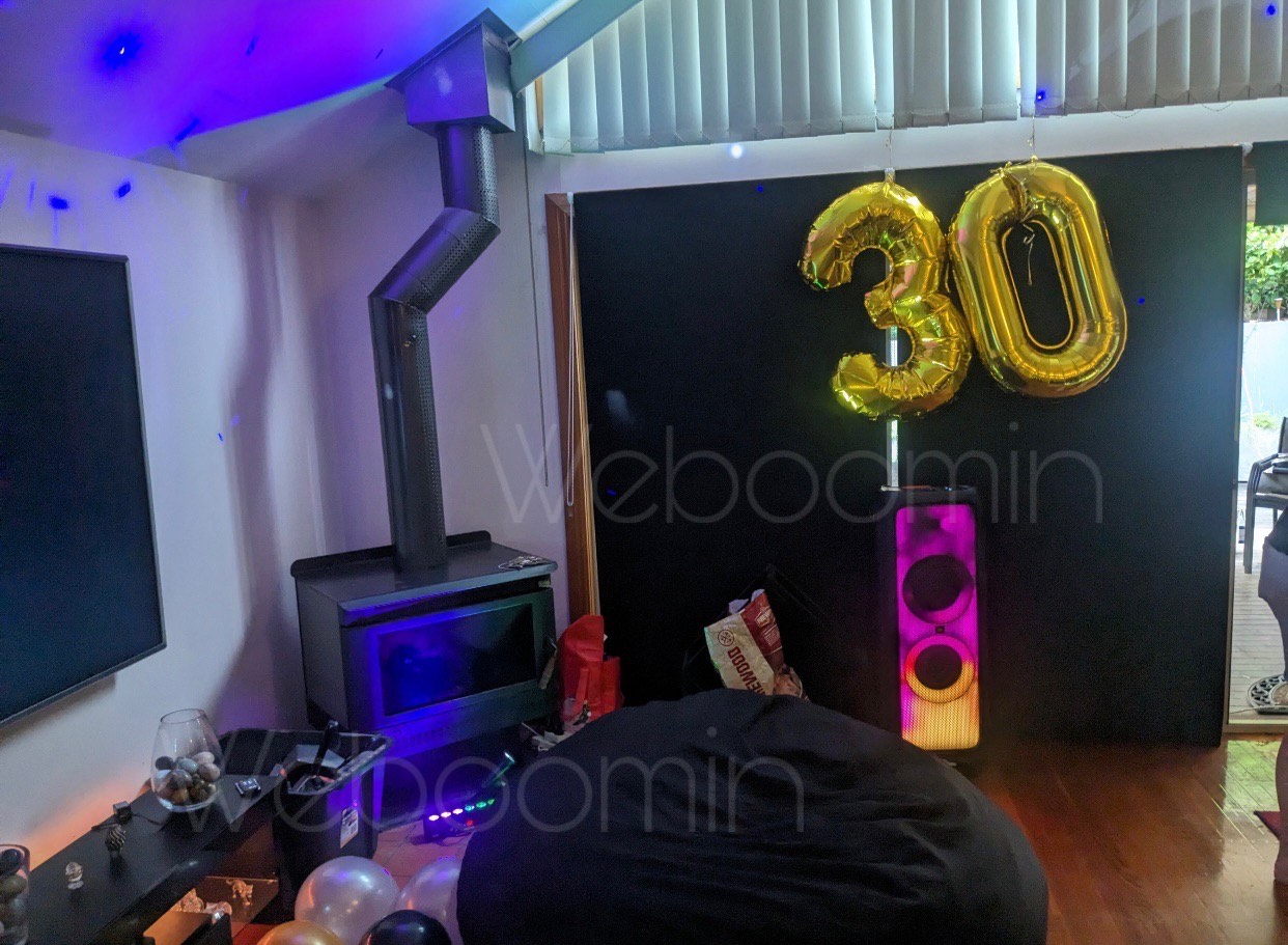 30th birthday lounge setup with a party speaker and gold balloons