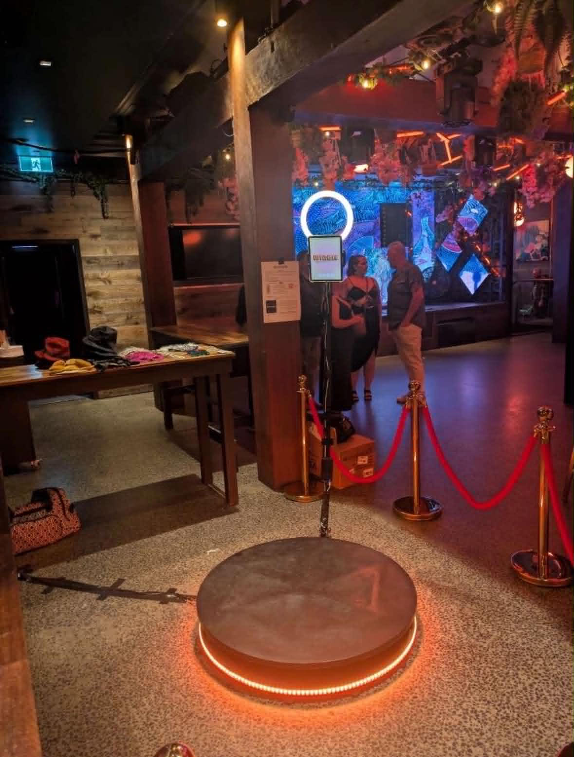 Nightclub 360 photo booth setup with warm orange lighting and velvet rope entry